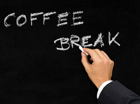 Man writing the words 'coffee break' on blackboard with chalkの写真素材