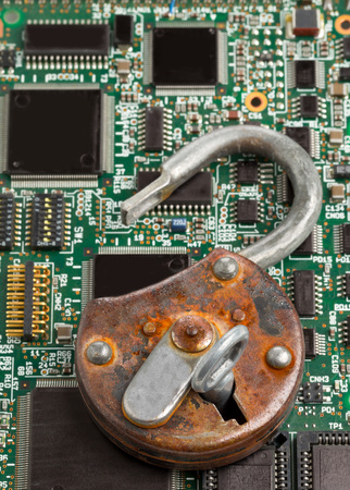 Old rusty open padlock on computer mainboard - information or data security conceptの写真素材