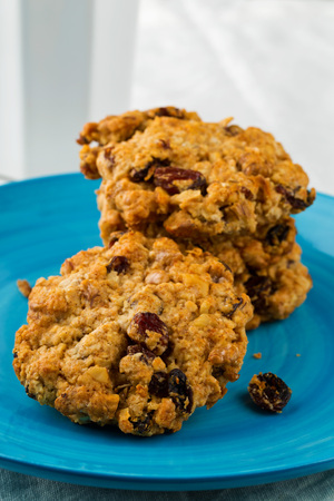 Oatmeal, walnut, raisin and cranberry cookies on blue plateの写真素材
