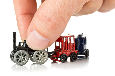 Man playing with old metal toy train with locomotive and wagons over white backgroundの写真素材