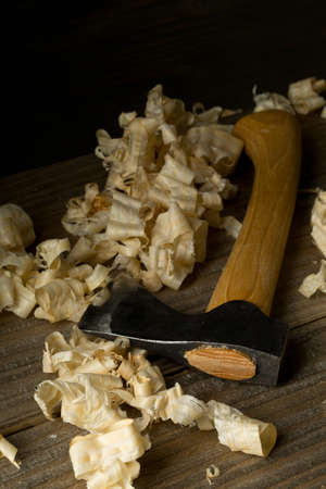 Woodworking carving axe tool on wooden boards in carpenter's workshop against dark brown background with copy spaceの写真素材