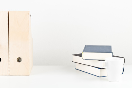 White office desk with books, cup and folders - copy space - study or workplace background mock up