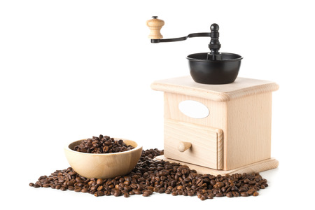 Coffee beans in wooden bowl with wooden coffee bean grinder over white backgroundの写真素材