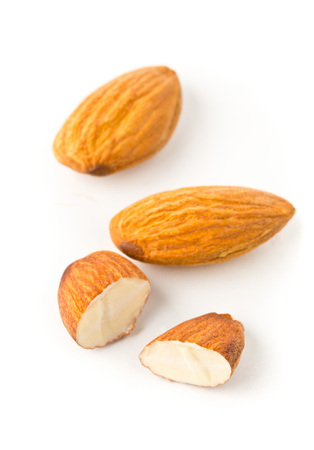 Macro of full and halfed shelled almond kernels with selective focus over white backgroundの写真素材