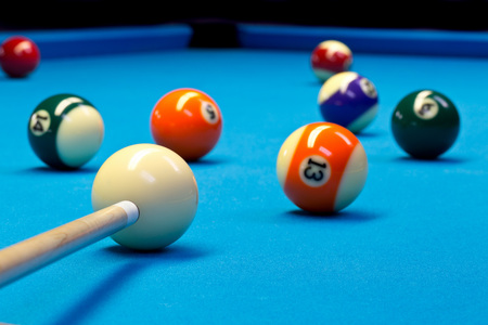 Billiard pool eightball taking the shot on billiard table with blue cloth, selective focus on white...