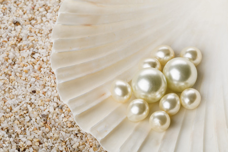 Multiple pearls in sea shell over sand backgroundの写真素材