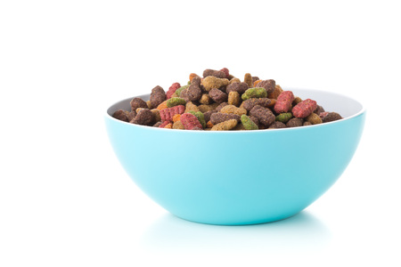 Heap of dry pet food in blue plastic bowl over white background