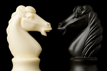Two black and white knight chess figures facing each other - conflict management, leadership or strategy concept over black backgroundの写真素材