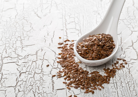 Raw, unprocessed linseed or flax seed in scoop on white table backgroundの写真素材