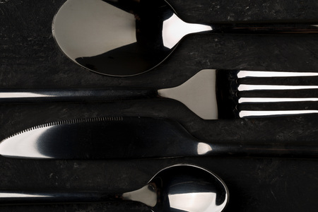 Kitchen cutlery set with spoons, knife and fork on dark background