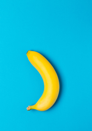 Single fresh, yellow, ripe banana over cyan backgroundの写真素材