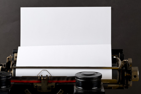 Close up of vintage typewriter with empty, blank sheet of paper on black backgroundの写真素材