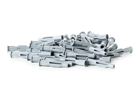Heap of unused, new, grey plastic wall plug bolts over white background
