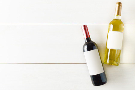 Red and white wine bottle on white wooden table flat lay from above with copy spaceの写真素材