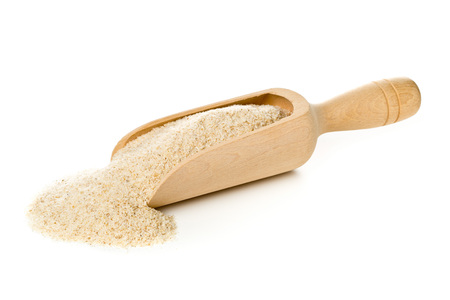 Heap of psyllium husk in wooden scoop over white background. Psyllium husk also called isabgol is...