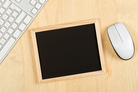Empty, blank, black chalkboard with computer mouse and keyboard on brown wooden table flat lay from above with copy space - e-learning or computer science conceptの写真素材