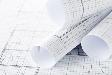 Rolls of architectural blueprint house building plans on blueprint background on table