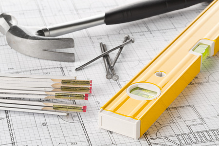 Construction tools  with hammer, nails, folding rule and level on architectural blueprint plan...