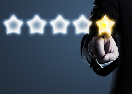 Business man in suit pointing at five star rating stars, selecting top rating; blue backgroundの写真素材