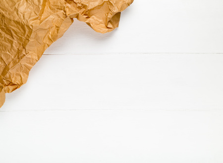 Crumbled brown packing paper on white wooden kitchen table with copy spaceの写真素材