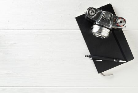 Retro analog film camera with notebook and pen on white wooden table background with copy space - photography, journalism, blogging or creativity concept, flat lay top view from aboveの写真素材