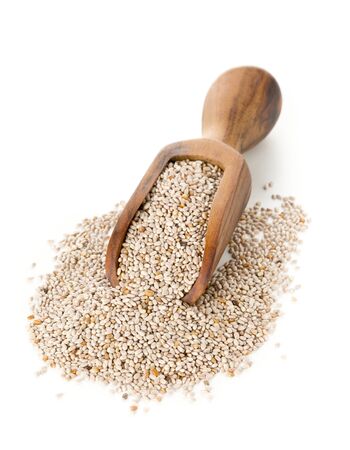 Whole, organic white chia seeds heap in brown wooden scoop over white backgroundの写真素材