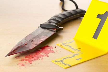 Crime scene investigation CSI evidence marker with bloody knife on wooden floor background at crime scene - police, evidence or forensic investigation concept, selective focusの写真素材