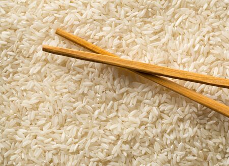 White uncooked, raw long grain rice full frame with chopsticks top view flat lay from above - selective focusの写真素材
