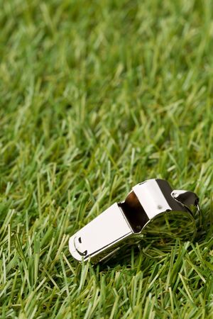 Soccer sports silver chrome whistle on grass background - penalty, foul or sports concept, selective focusの写真素材