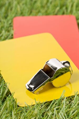 Soccer sports referee yellow and red cards with chrome whistle on grass background - penalty, foul or sports concept, selective focusの写真素材