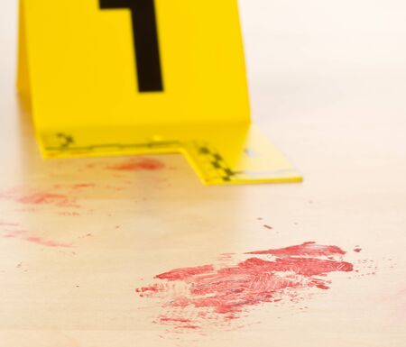 Crime scene investigation CSI evidence marker with blood spot on wooden floor background at crime...