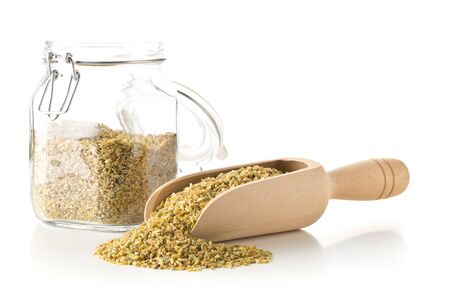 Heap of uncooked, raw freekeh or firik, roasted wheat grain, in wooden scoop and glass storage jar over white backgroundの写真素材