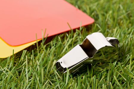 Soccer sports referee yellow and red cards with chrome whistle on grass background - penalty, foul or sports concept, selective focusの写真素材