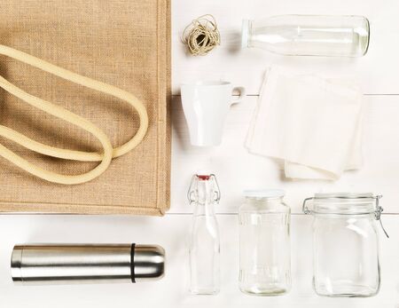 Zero waste or waste free shopping utensils with burlap bag, glass bottles and cotton bag on white wooden table background flat lay from above - waste reduction eco lifestyle or bulk buy grocery conceptの写真素材