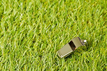 Soccer sports silver chrome whistle on grass background - penalty, foul or sports concept, selective focusの写真素材