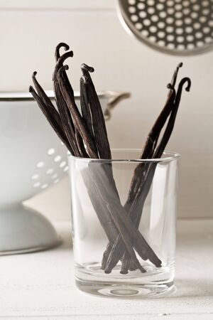 Bundle of dried bourbon vanilla beans or pods in glass on white kitchen background - selective focusの写真素材