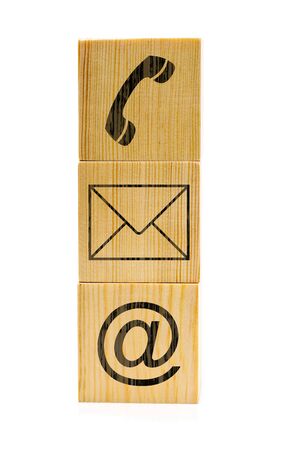 Contact us symbols with phone, e-mail and envelope icons on stacked brown wooden cubes on white backgroundの写真素材