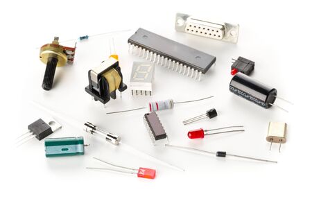 Different electronic parts or components on white background with resistors, capacitors, diode and...