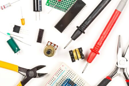 Different electronic parts or components, pliers and measurement device on white background with...