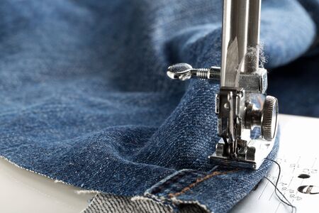 Blue jeans denim sewed on sewing machine close up - jeans fashion mending or repair concept,...