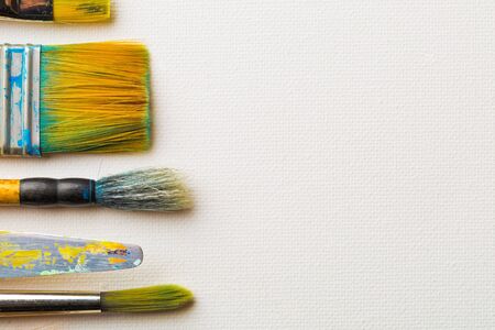 Artistic art supply utensils with paintbrushes on white canvas background with copy space flat lay top view from aboveの写真素材