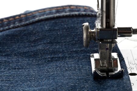 Blue jeans denim sewed on sewing machine close up - jeans fashion mending or repair concept,...