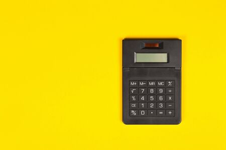 Pocket calculator on yellow background with copy space - minimal modern tax, finance or accounting concept, top view flat lay from aboveの写真素材