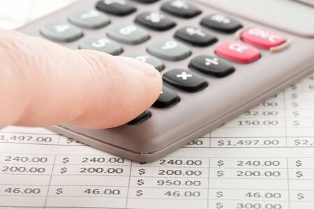 Man working with pocket calculator on financial analysis sheet background - tax, finance or...