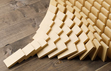 Wooden domino stones pyramid on wood floor falling over, chain reaction or multiplication effect concept, 3D illustrationの写真素材