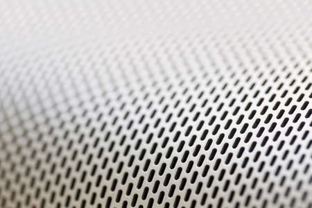 Abstract background macro shot of shiny aluminum metal sheet with holes, selective focusの写真素材