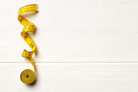 Tape measure sewing tool over white wooden table background with copy space, top view flat lay from aboveの写真素材