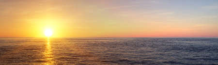 Wide panorama view of sunset or sunrise of open ocean or sea with blue sky and few, small clouds, 3D...