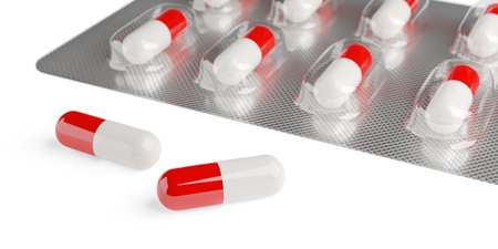 Red and white pill capsules in pill blister pack on white background with selective focus, medicine,...