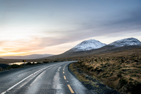 A curving road going towards a snow covered mountainの写真素材